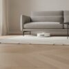 Robot aspirateur en cours de passage sous un canapé dans un salon en parquet clair Robot aspirateur en cours de passage sous un canapé dans un salon en parquet clair