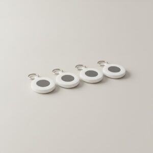 Lot de quatre traceurs Bluetooth ronds présentés côte à côte sur fond gris clair