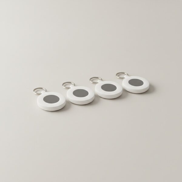 Lot de quatre traceurs Bluetooth ronds présentés côte à côte sur fond gris clair Lot de quatre traceurs Bluetooth ronds présentés côte à côte sur fond gris clair